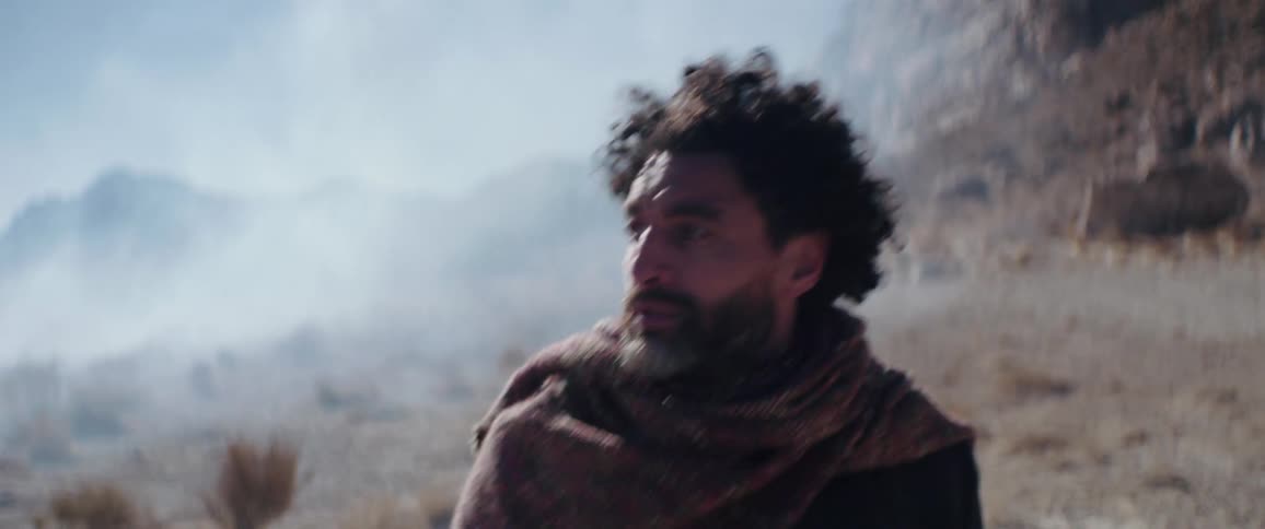 A man is walking in a smoky desert near cliffs