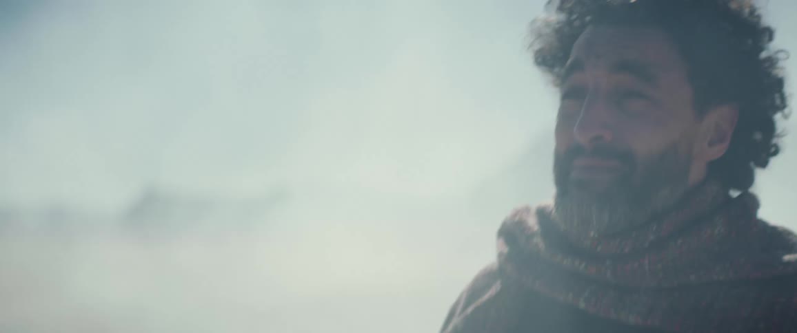A man walking through fog dust and wind calling for the person hes looking for