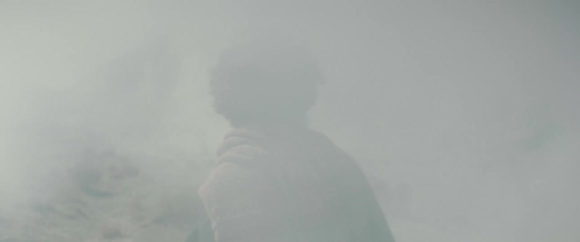 A man walks through the fog talking