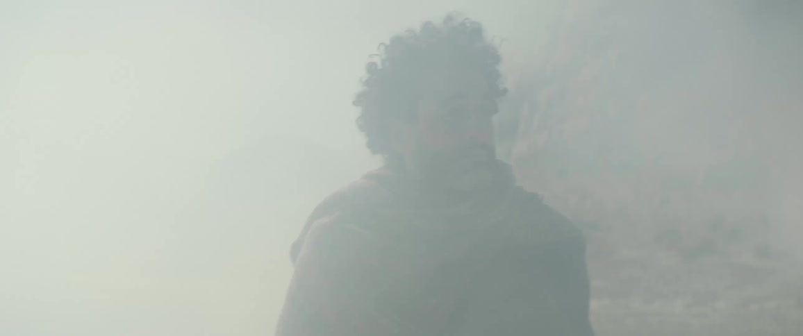 A man calls out as he walks through dust storm in a desert