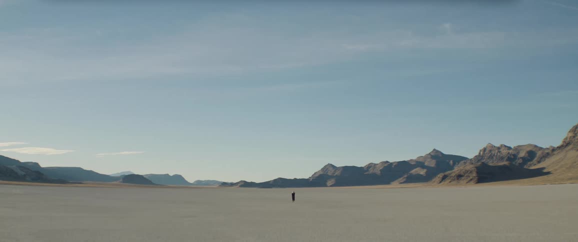 A person walks through an empty arid flatland during the day