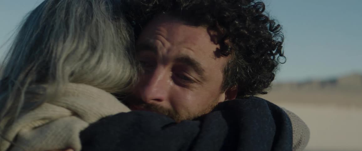 A man stretches his hand out to a woman as he walks toward her then they embrace
