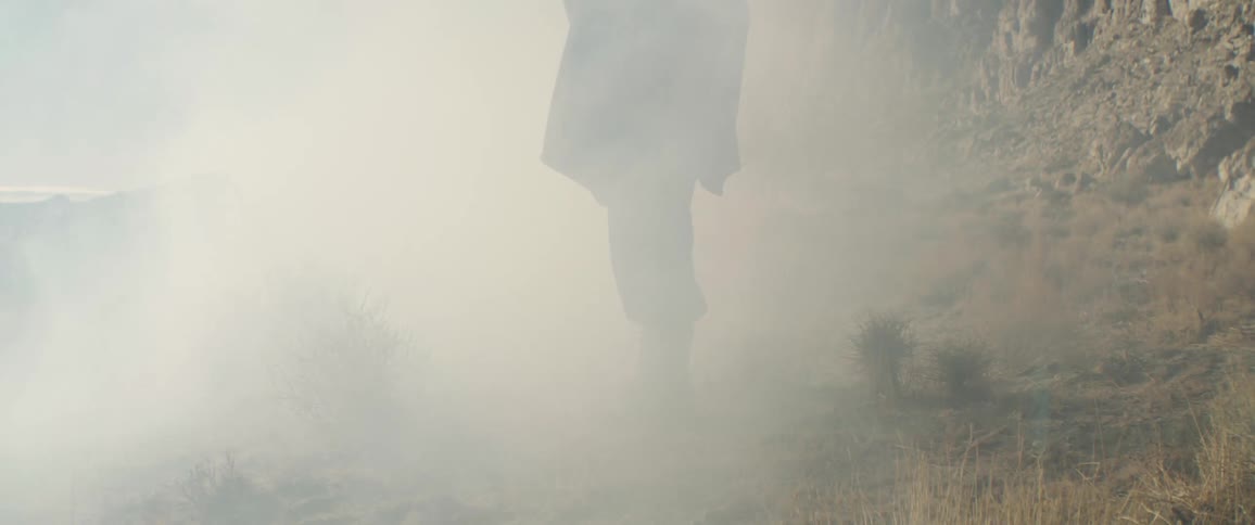 Fog rolls past the person by the mountain