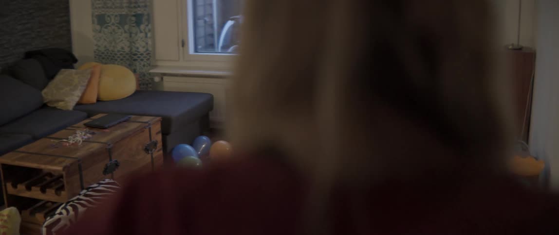 A woman walks into a room strewn with toys and balloons