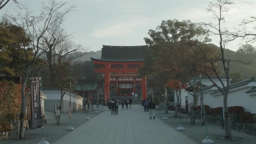 People walk down a concrete pathway toward an arch