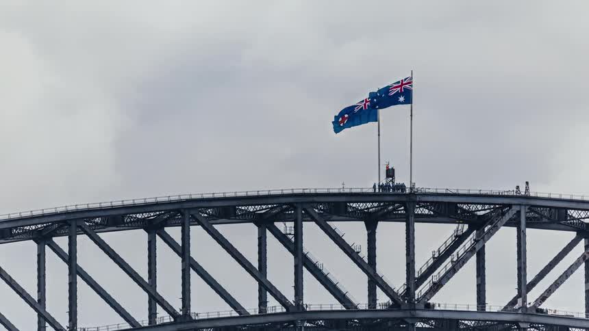 A time lapse of a group of people lining up on a bridge and walking to two flags