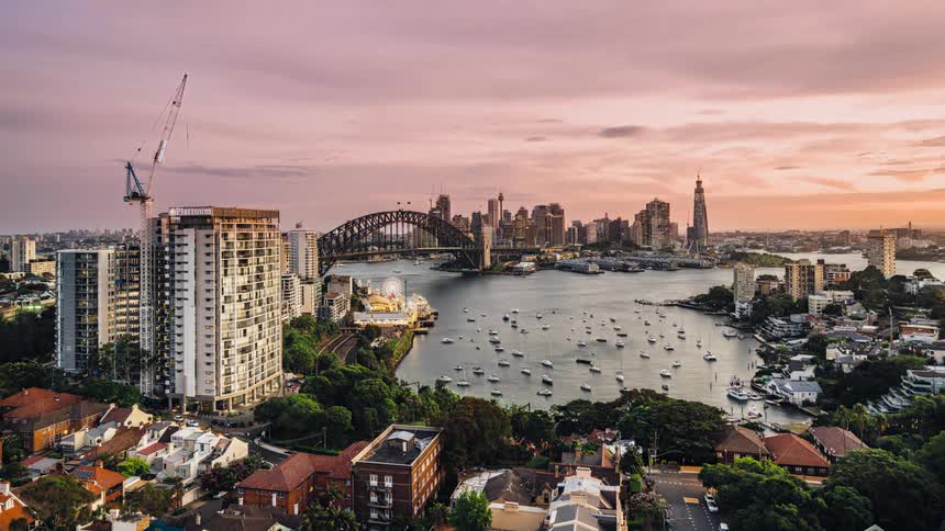 The sydney harbor bridge and city skyline with boats traveling and docked