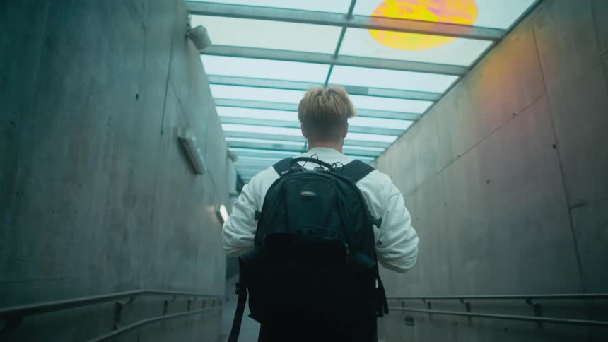 A man is walking through an empty building and wearing a backpack