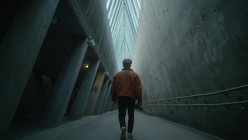 A man walking through a corridor with a camera in hand