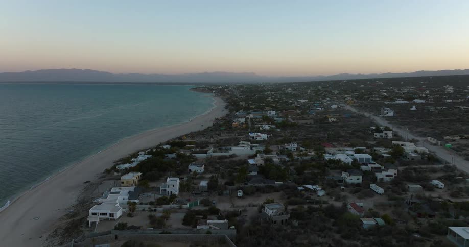 Beach side town stretches to mountains on horizon sitting under a red sky