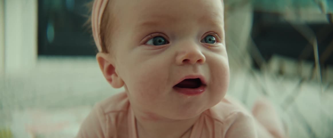 A baby girl crawls on the floor in her living room