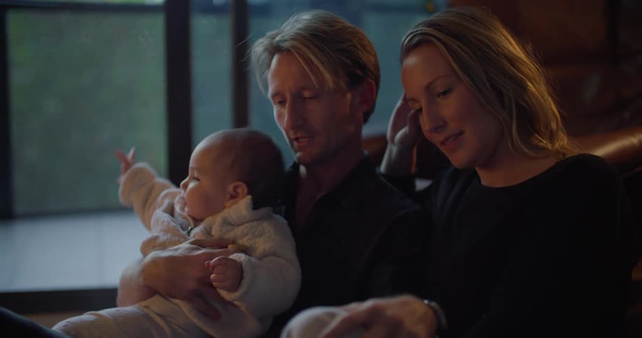 Father holds child as he and mother sit together closely and talk