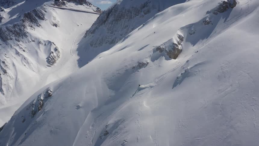 A skier coasts down the side of a snow covered mountain