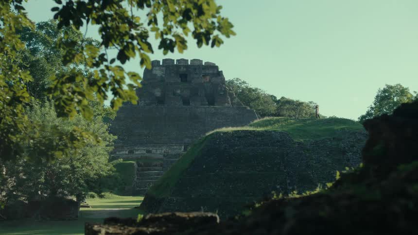 People climb mound on manicured lawn near tower