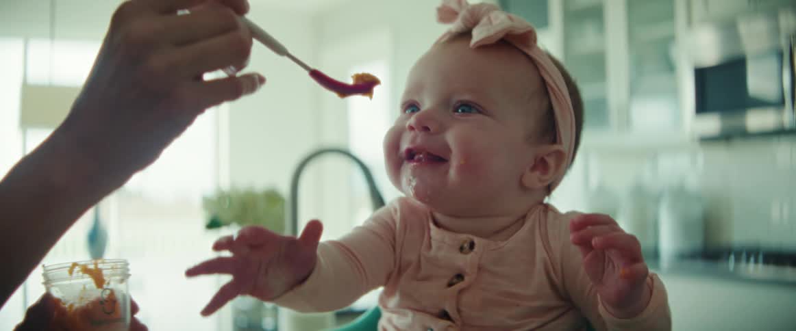 Mother is feeding her baby daughter some food