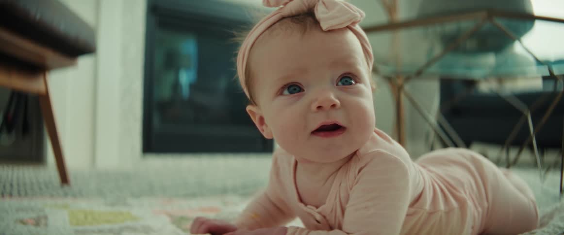 Baby girl lying on her stomach looks around then starts smiling and laughing
