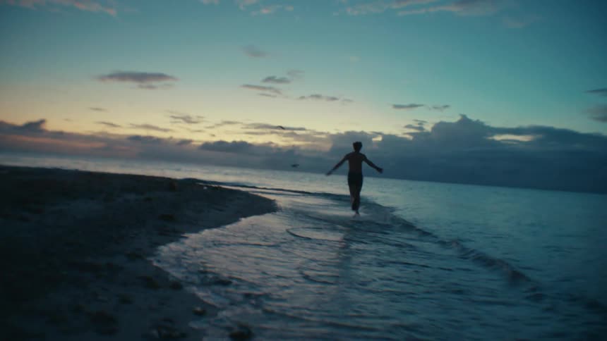 A person is running outside in the daytime by the ocean