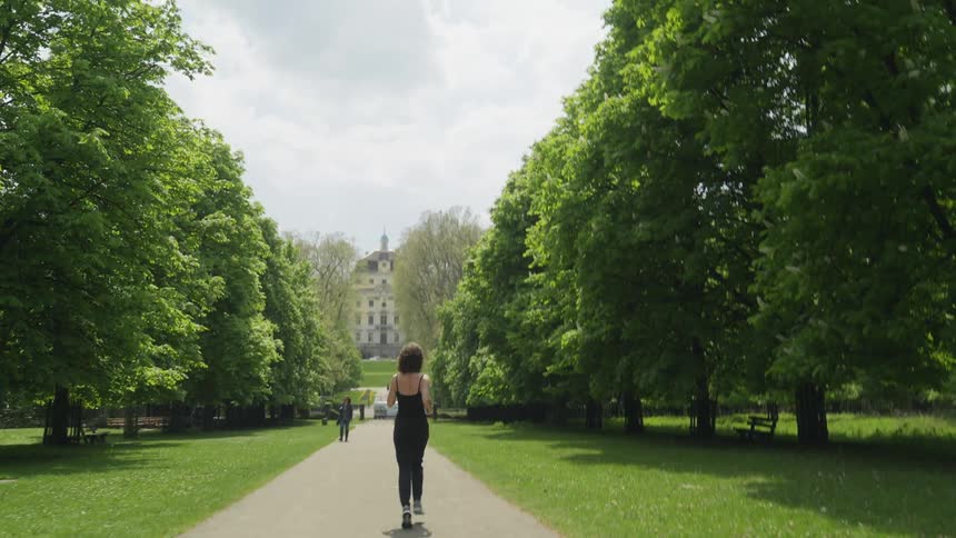 A woman is jogging outdoors at a public park during spring