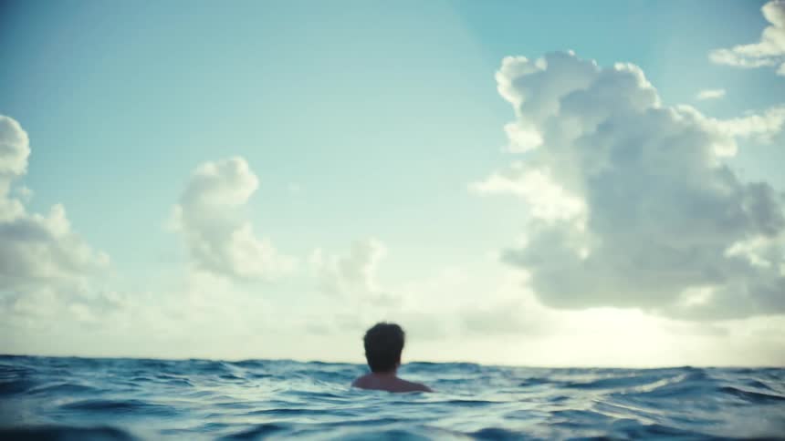 Man wading out in the middle of the ocean by himself