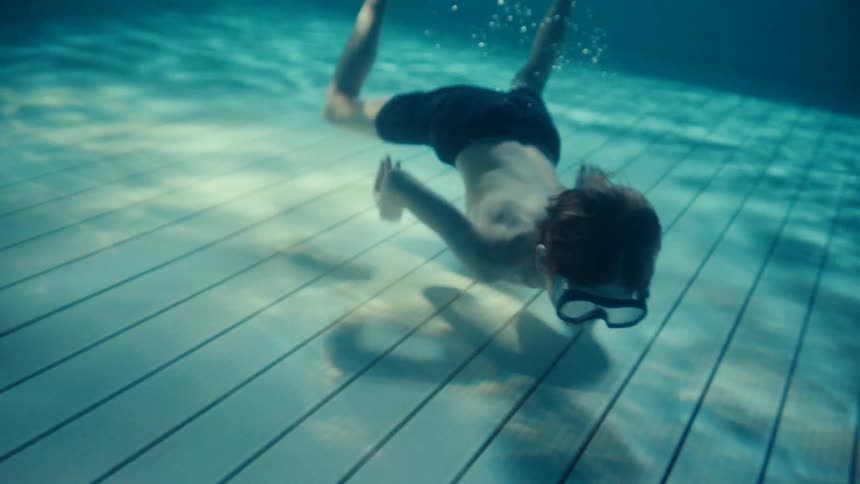 Boy wearing a swim mask swims underwater and periodically surfaces