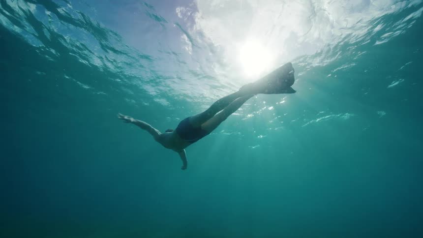 A person is swimming under the ocean water