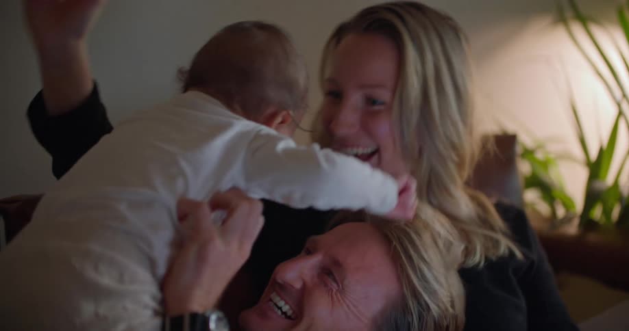 A couple play with their baby on the couch