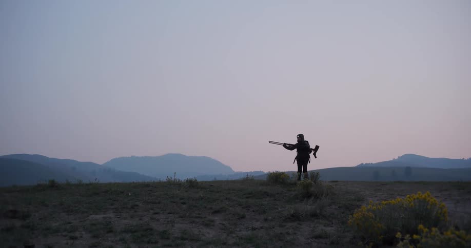 A photographer setting up a tripod in a field at sunset