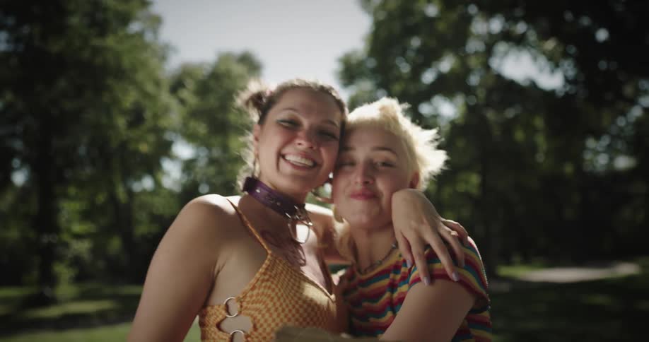 Two teenage girls hug and laugh as one holds up a free hugs sign