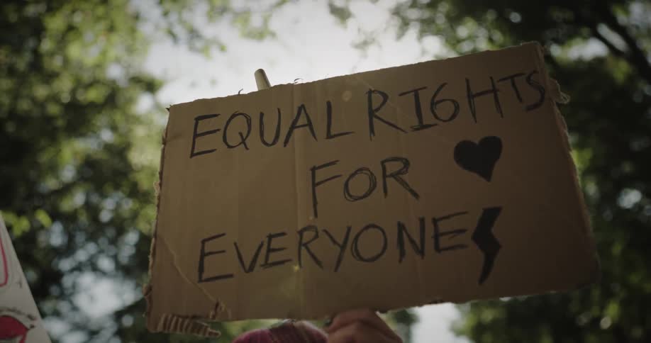 Someone is standing outside holding a sign promoting equal rights for everyone