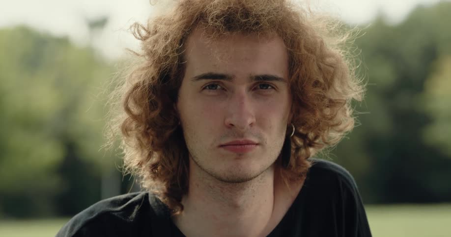 A man sits in a public park and poses for a portrait