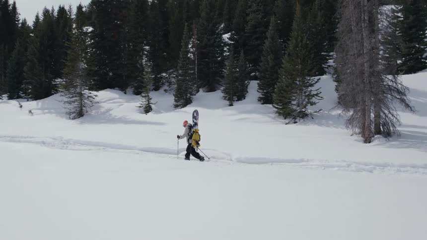 A person is hiking through a wooded area during winter