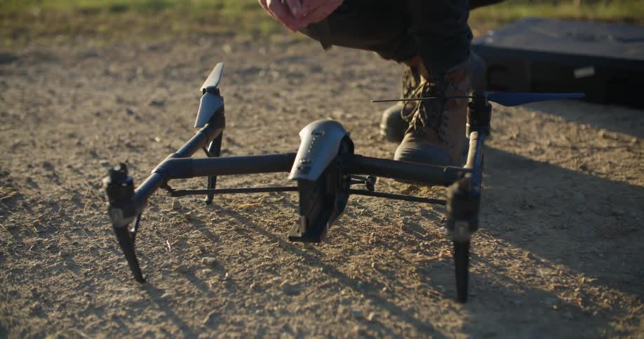 A man is putting together a robotic drone outdoors