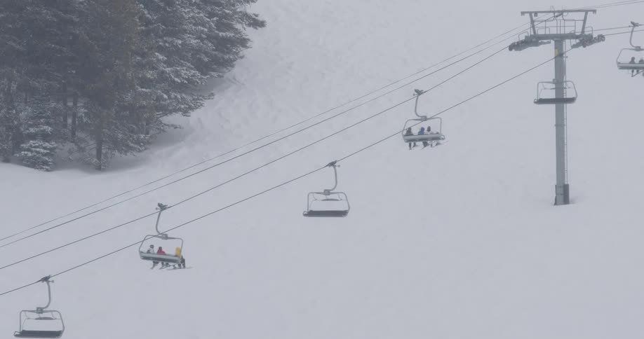 People are skiing and on a lift on slopes in the winter time