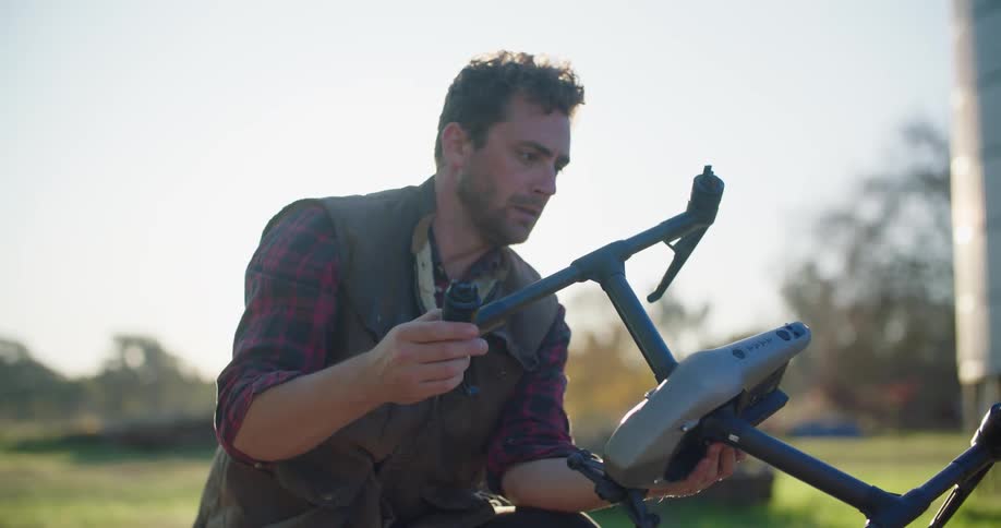 A man lifts a drone out of the case and holds it in his hands as he inspects it