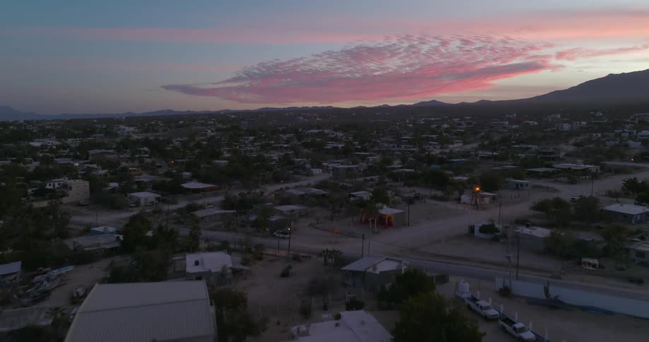 Red tinted clouds sits on horizon over mountains bordering town