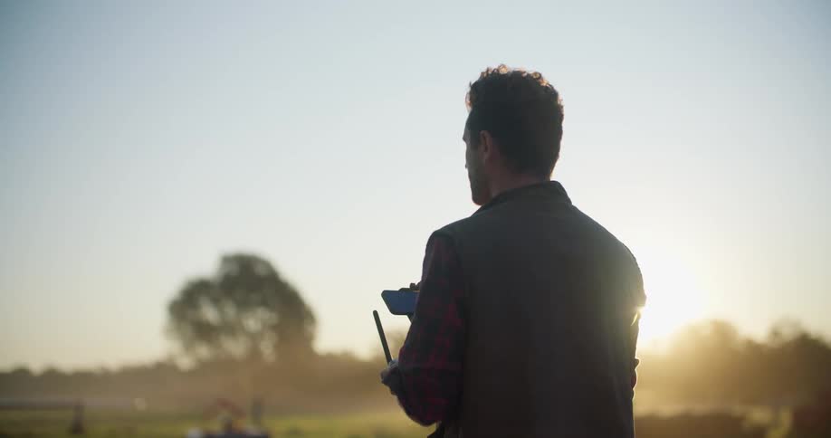 A man is flying a drone outdoors in a rural area