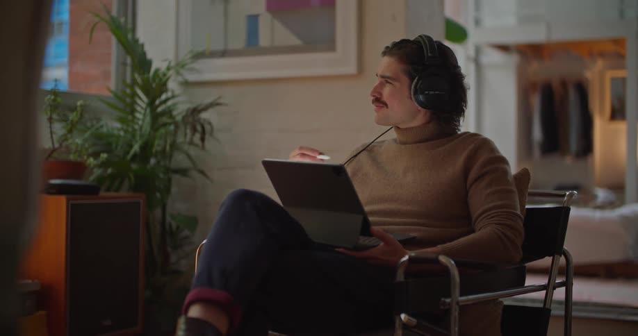 A man is sitting in a chair and browsing on a laptop