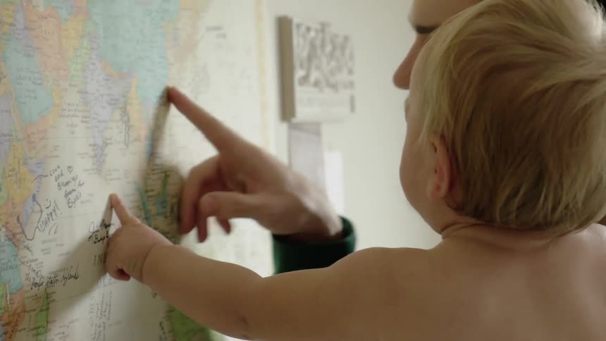 A man points to a map while holding a baby