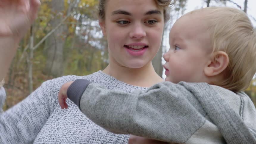 A woman holding a toddler and encouraging them to look up at something