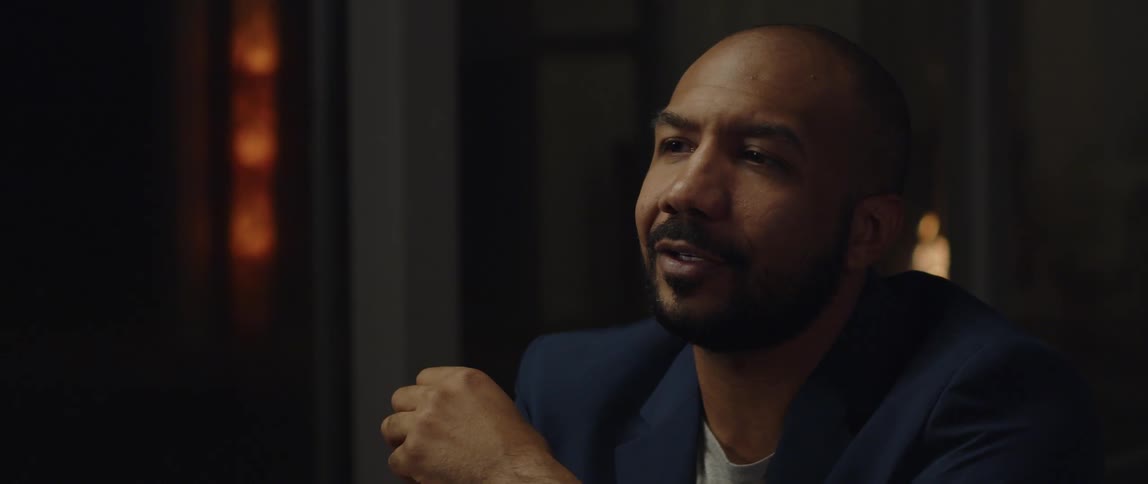 A black man is relaxing indoors wearing a suit