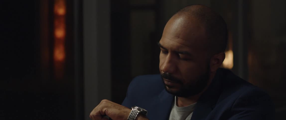 A man checks his watch while sitting indoors