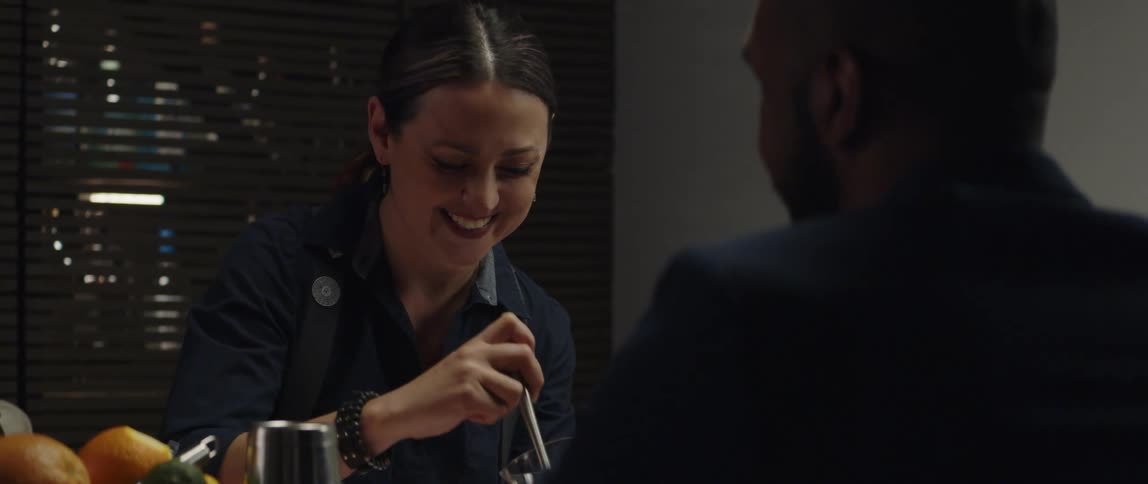 Woman stirs contents of glass as she talks and laughs with man