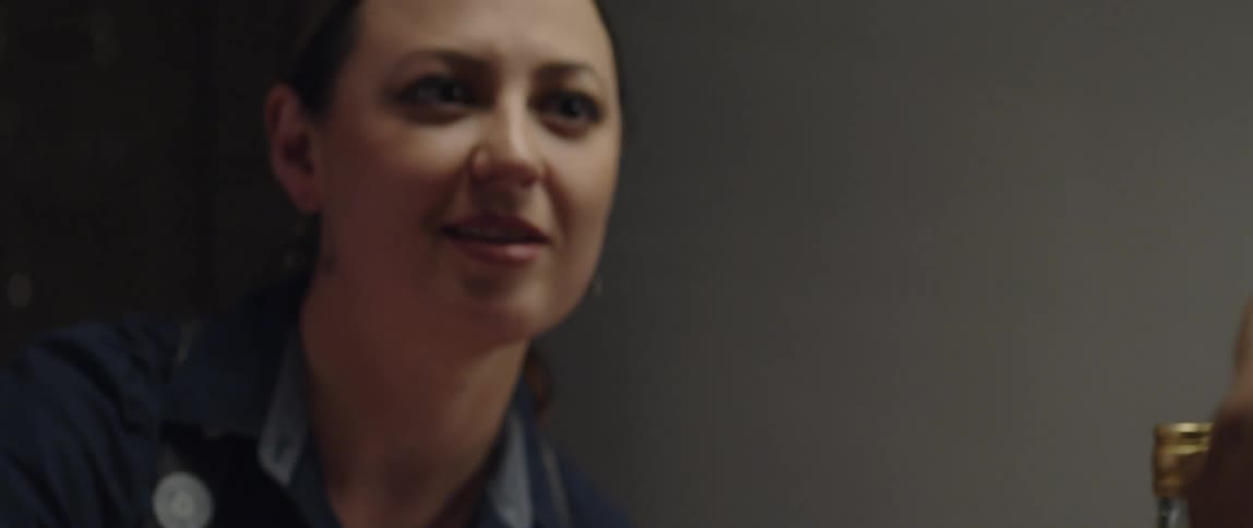 A woman is talking to someone drinking an alcoholic beverage