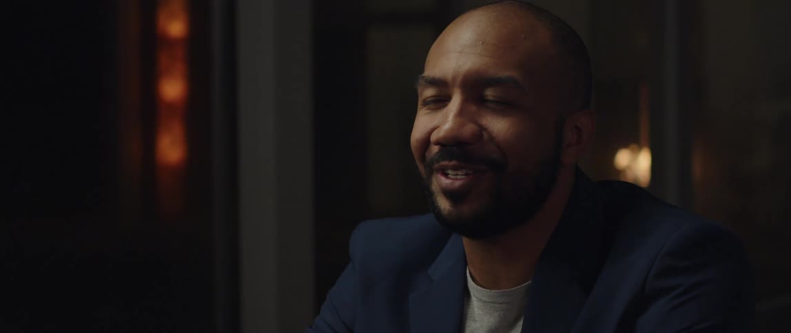 A black man is wearing a suit and laughing