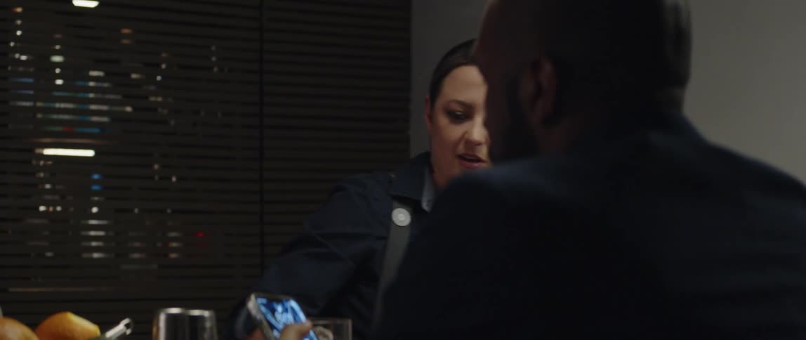 Female bartender preparing drink as a patron checks his phone sitting at the bar counter