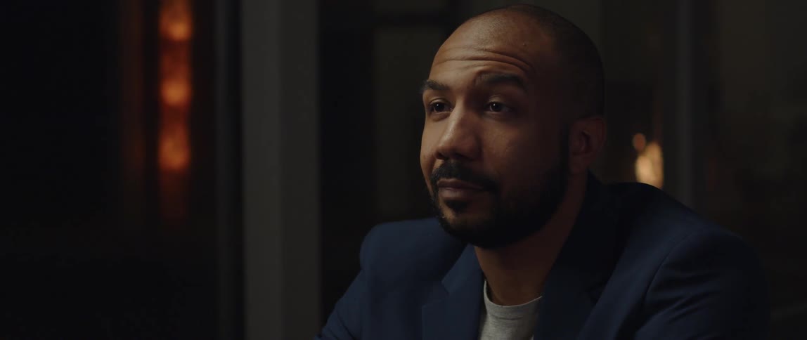A man is sitting in a room and wearing a suit