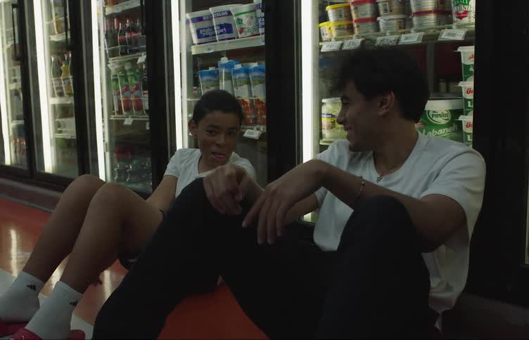 A boy and a teen are sitting down in a grocery store