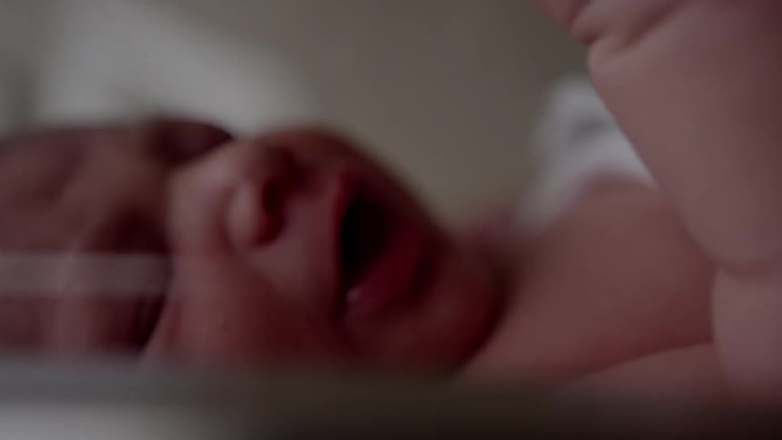 A baby throws its arms up while crying