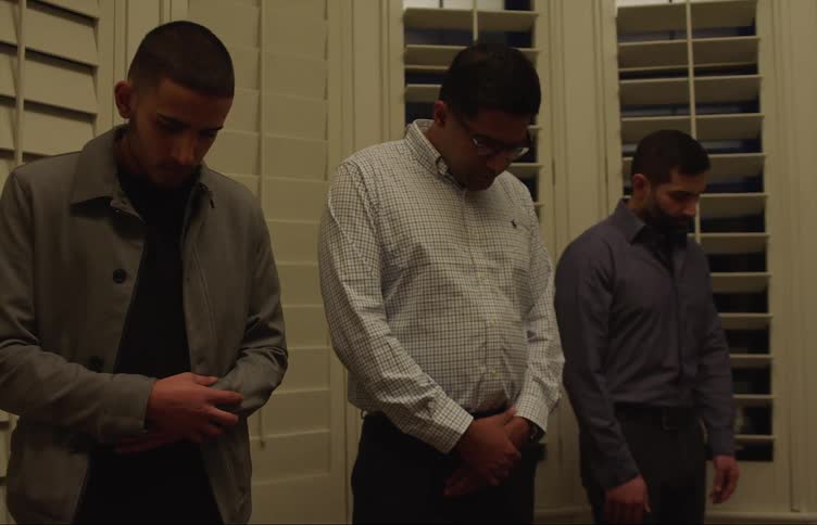 Three men stand in prayer at home