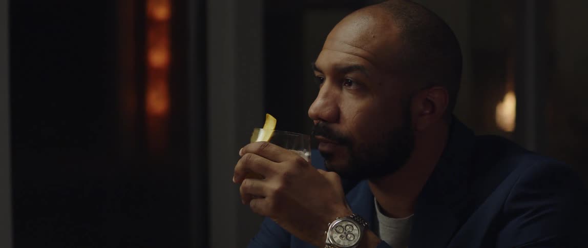 A man is sitting down and drinking alcohol